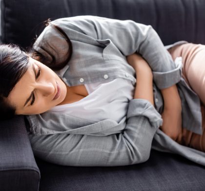 attractive woman suffering from stomach ache in living room